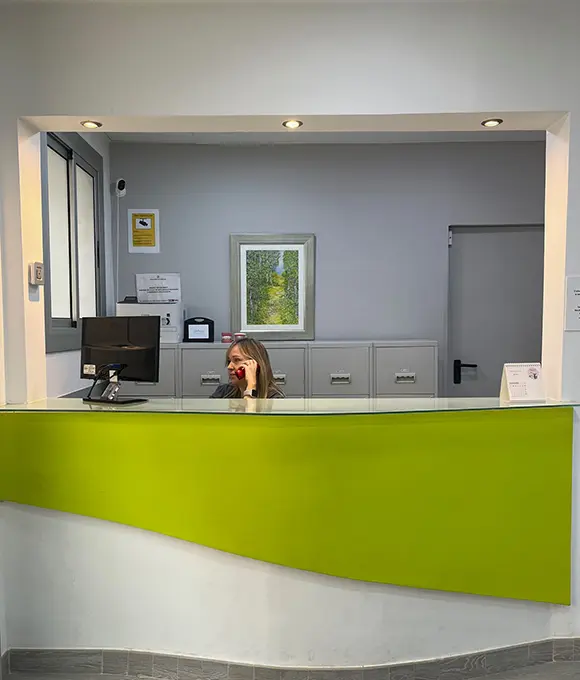 Patricia atendiendo el teléfono en la recepción de la Clínica Dental Vilà, ofreciendo un servicio al cliente profesional