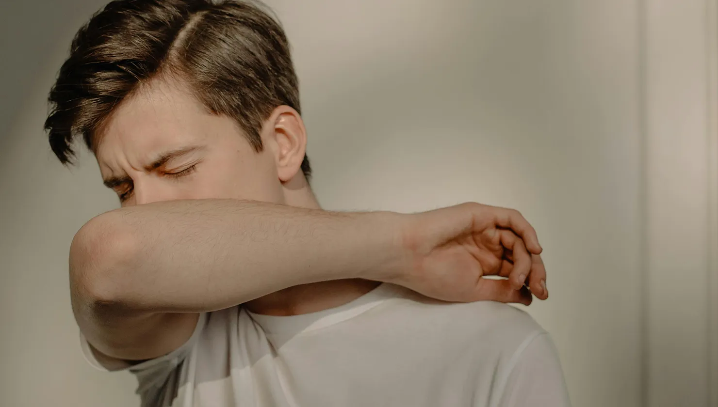 Chico con alergia protegiéndose la boca