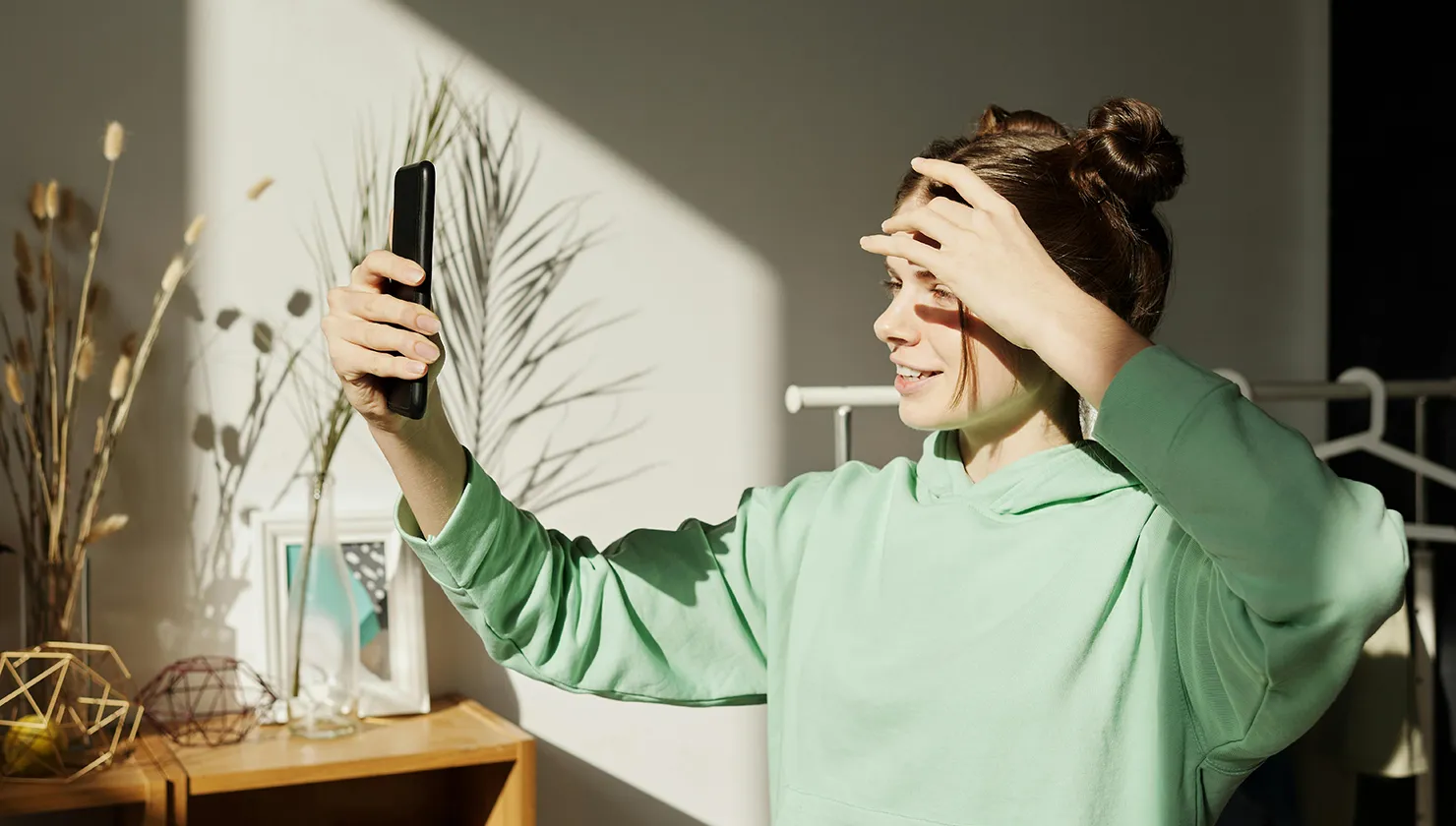 Noia jove fent-se un selfie a l’aire lliure mentre somriu amb dents cuidades