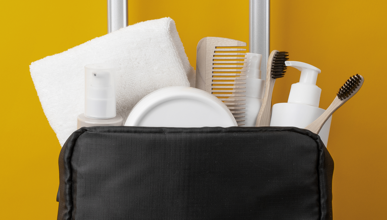 Necesser de viatge amb raspall de dents, pasta dental i fil dental sobre una tovallola, ideal per mantenir la higiene bucal durant les vacances d’estiu