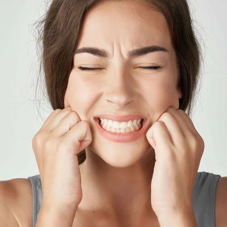 Imatge d'una persona aguantant-se la mandíbula per dolor causat pel bruxisme, afectant la salut dental i l'estètica del somriure.