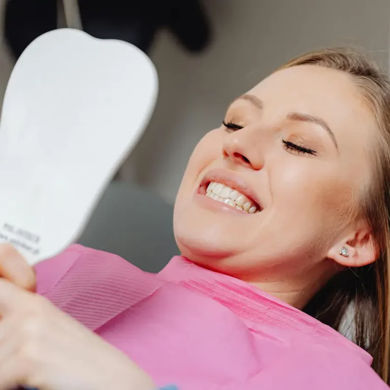 Pacient feliç mirant el seu somriure al mirall després d’una revisió dental a la clínica dental vilà.