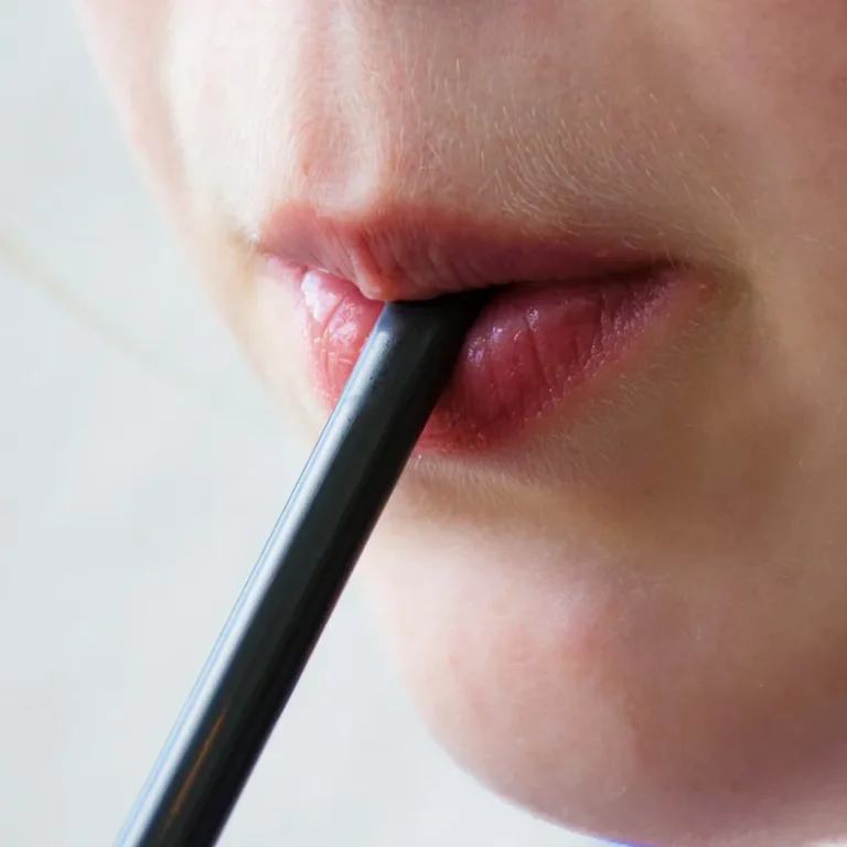 Primer pla d'una boca bevent una beguda freda amb canya, ideal per reduir el contacte del sucre amb les dents