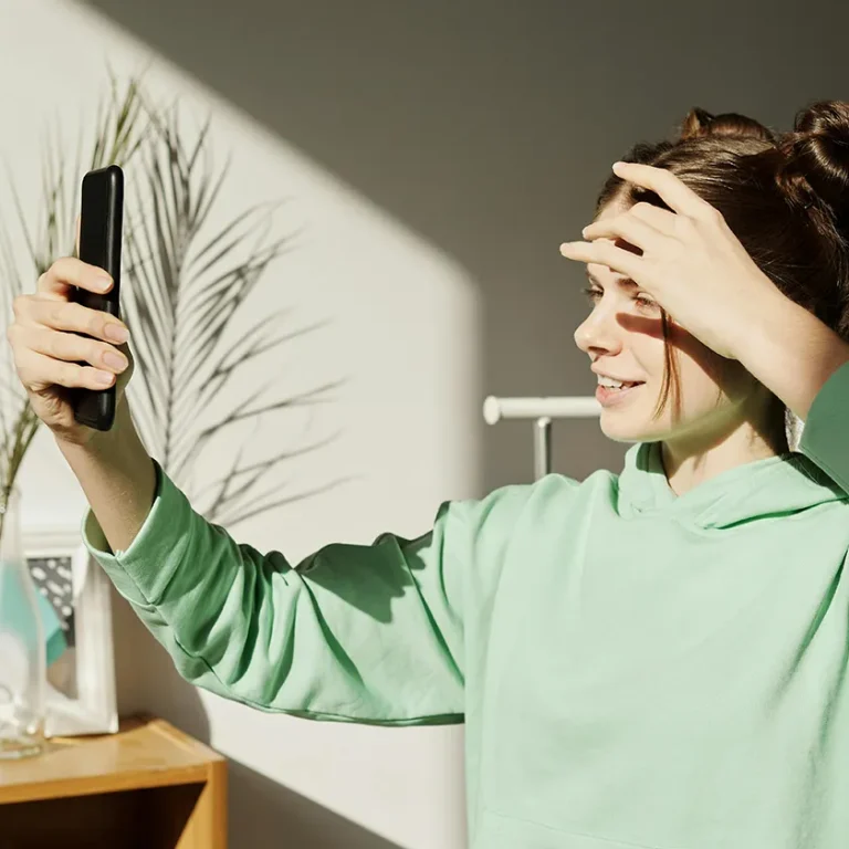 Noia jove fent-se un selfie a l’aire lliure mentre somriu amb dents cuidades