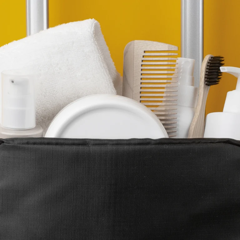 Necesser de viatge amb raspall de dents, pasta dental i fil dental sobre una tovallola, ideal per mantenir la higiene bucal durant les vacances d’estiu