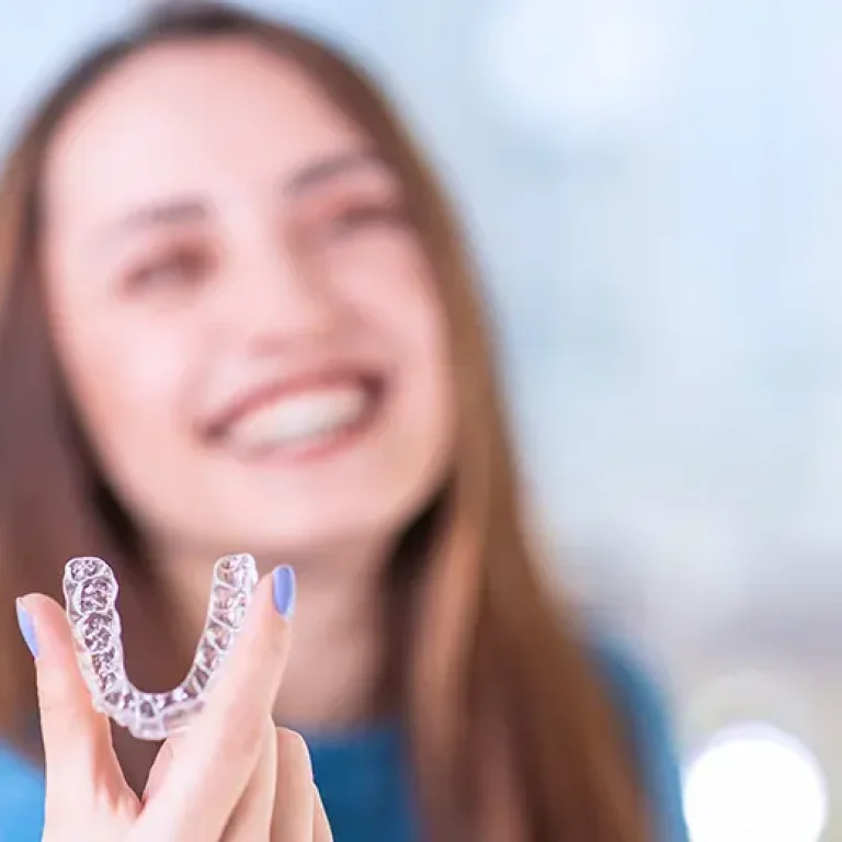 Chica sosteniendo una ortodoncia invisible, tratamiento de ortodoncia de Clínica Dental Vilà para una sonrisa perfecta y discreta